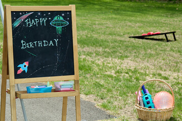 Chalkboard 1st Birthday Sign with UFO Drawing on Grass

