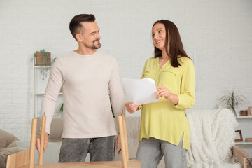 Happy pregnant couple with manual assembling shelving unit at home
