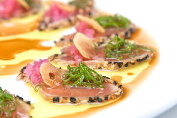 Tuna sashimi, sliced ​​tuna fillet with black sesame, olive oil and teriyaki sauce, food close up view	