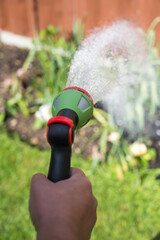Male hand with hose and water jet watering the garden