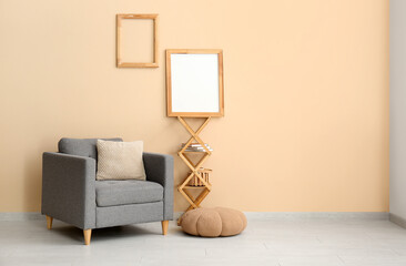 Armchair with pouf, shelves and photo frames on beige wall