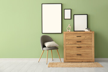 Commode with chair and empty posters on green wall
