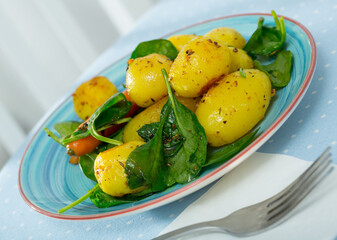 Vegetarian dish. Delicious baked new potatoes with spinach garnished with carrots..