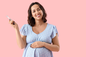 Young pregnant woman with lancet pen on pink background. Gestational diabetes concept