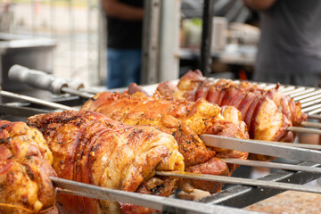 rolled pork belly skewer roasting on street barbecue
