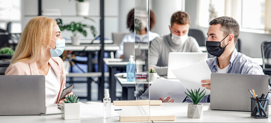 New normal and communicate with protection. Millennial man and woman in protective masks work with...