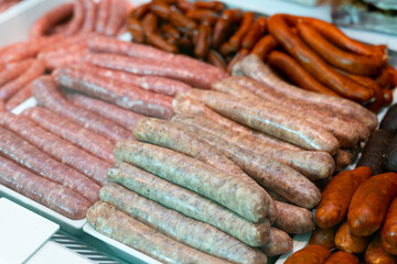 Variety of traditional spanish sausages arranged in glass display case of butchery shop. Popular...