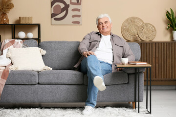 Fototapeta premium Happy senior man sitting on sofa in living room