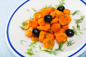 Steamed carrot slices roasted with glaze, garnished with black olives and herbs
