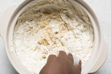 Overhead view of homemade pretzels dough being kneaded in a bowl, top view of soft pretzel dough on a white background