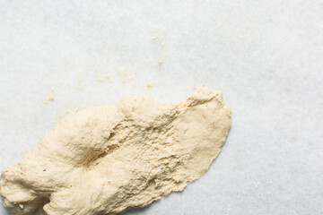 Overhead view of homemade pretzels dough being kneaded on a white countertop, top view of soft pretzel dough on a white background
