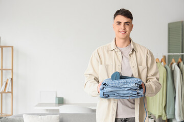Young man with steamer and jeans clothes at home