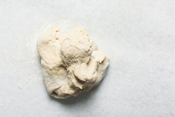 Overhead view of homemade pretzels dough being kneaded, top view of soft pretzel dough on a white background