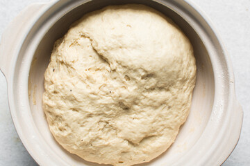 Overhead view of proofed homemade pretzels dough in a bowl, top view of soft pretzel dough on a white background