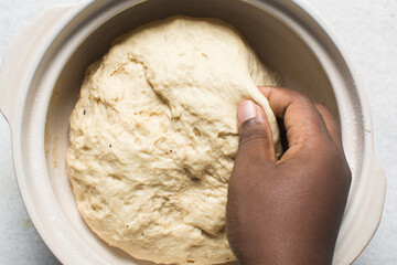 Overhead view of proofed homemade pretzels dough in a bowl, top view of soft pretzel dough on a white background