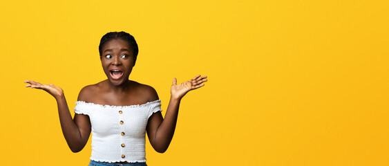 Surprised african american lady spreading hands in excitement and looking at copy space, amazed...