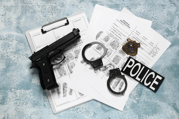 Handcuffs, fingerprints sheets, gun and police shield on blue background