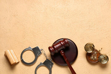 Judge's gavel, scales of justice, handcuffs and stamp on beige background