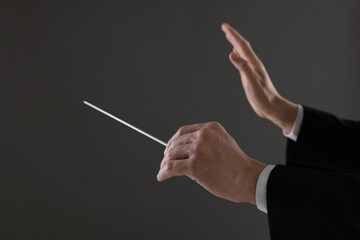 Conductor with baton on grey background, closeup