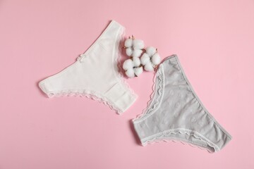 Women's underwear. Beautiful panties and cotton flowers on pink background, flat lay
