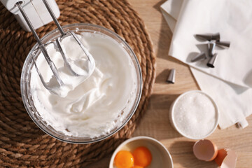 Hand mixer with whisks, bowl of whipped cream and ingredients on table, flat lay
