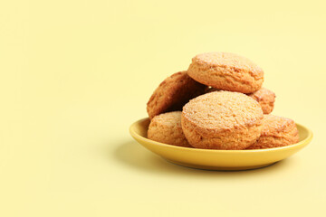 Plate with sweet cookies on yellow background