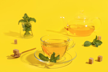 Cup of fresh mint tea on yellow background
