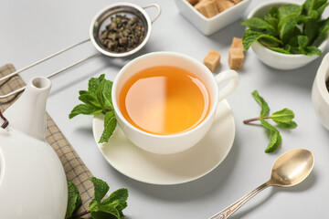 Cup of fresh mint tea on light background