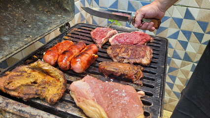 A delicious barbecue on the grill with different meats being prepared.