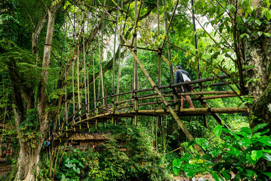 A person walks on a traditional and environmentally friendly bamboo bridge