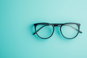Modern eyeglasses resting on vibrant teal background with copy space