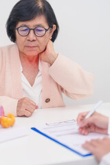 Elderly Patient having Neck pain and consulting  with Doctor to Thyroid disease. Anatomy Thyroid model for Hyperthyroidism, Hypothyroidism, Hashimoto Thyroiditis, Thyroid Tumor and Cancer