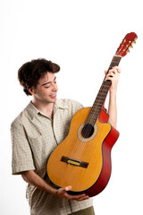 Upright portrait of young Latin man holding a guitar and looking at affectionately