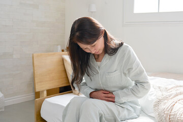 腹痛のパジャマを着た中年の女性