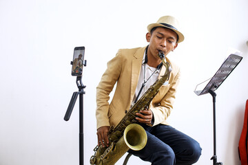 Young Influencer Man In Formal Suit Recording For Video Blog With Saxophone