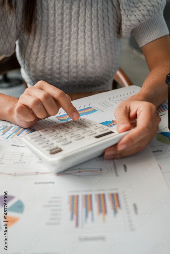 Poster close-up of a woman using a calculator with financial charts, emphasizing analysis and strategy in a