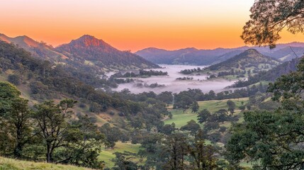 Fototapeta premium Serene Sunrise Over Misty Valley with Rolling Hills and Majestic Mountains in Background