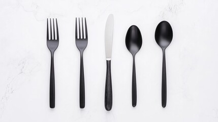 Modern black cutlery set arranged neatly on a white marble surface, including forks, a knife, and spoons.