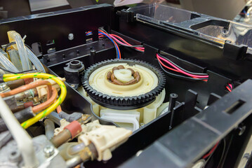Internal mechanism of automatic coffee machine with grinder gear, wiring and brewing unit exposed during maintenance or repair

