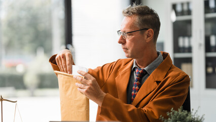 An elderly Caucasian male lawyer works at his desk in a law firm, offering legal advice and...