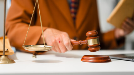 An elderly Caucasian male lawyer works at his desk in a law firm, offering legal advice and business law services. A gavel and documents symbolize justice and professionalism