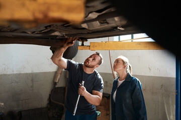 Mechanic, motor garage and working on car with training, maintenance engineer and teamwork at...