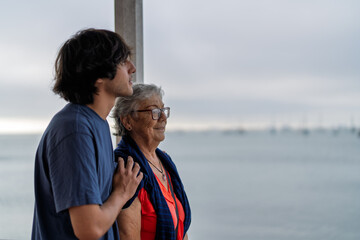 Grandson showing love and respect for grandmother by the sea