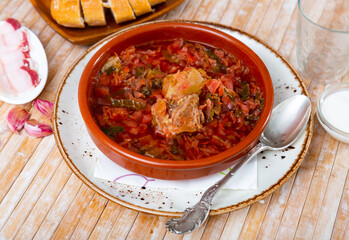 Just prepared borscht served in bowl with salo and serving pieces.