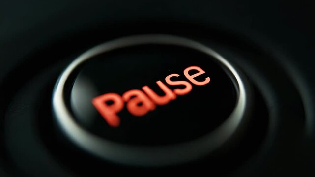 A close-up of a finger pressing an illuminated pause button on a black device.