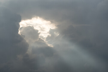 Sunlight breaking through storm clouds in dramatic sky evoking themes of hope, religion and spirituality