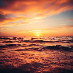 A beautiful orange sunset reflects on the calm sea along the sandy beach