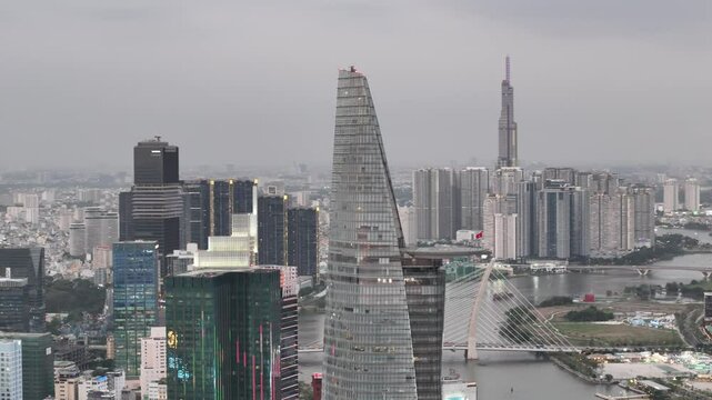 Raw aerial orbital view around the Bitexco Financial Tower and Landmark 81 in single frame in Ho Chi Minh City, Vietnam, showcasing the winding Saigon River. During dawn overlooking the city skyline