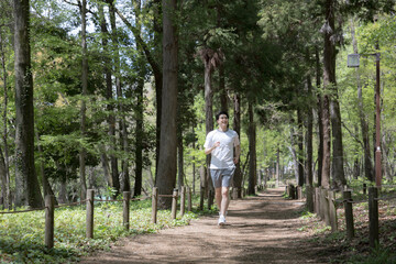 Obraz premium 公園や林道をランニングしながら空を見上げる男性のクローズアップ全身の広角