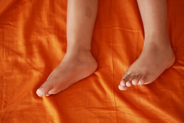 child Feet resting on an orange fabric surface at home
